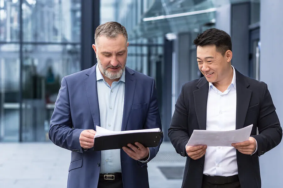 Matured businessman talking with middle-aged Asian businessman